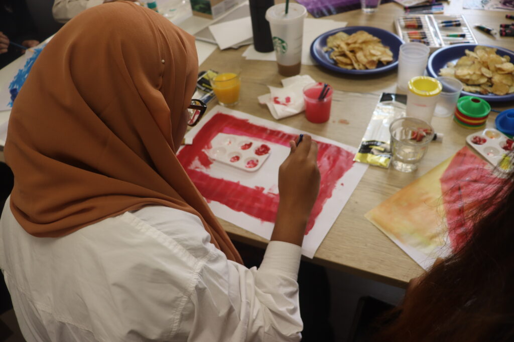 A young person takes part in a painting exercise as part of a workshop.